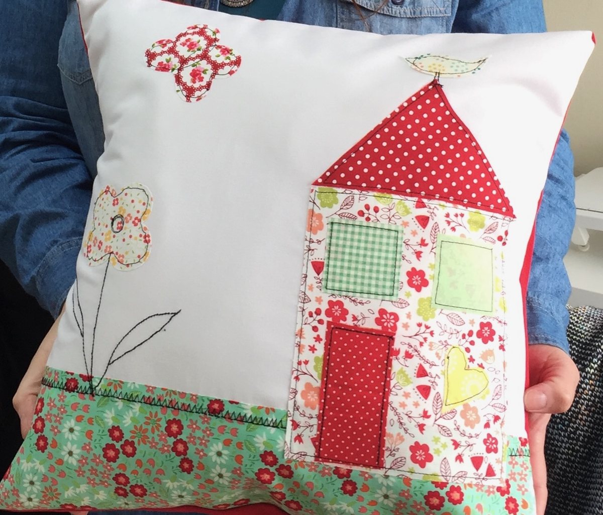 Cojín con una casita de patchwork roja y verde