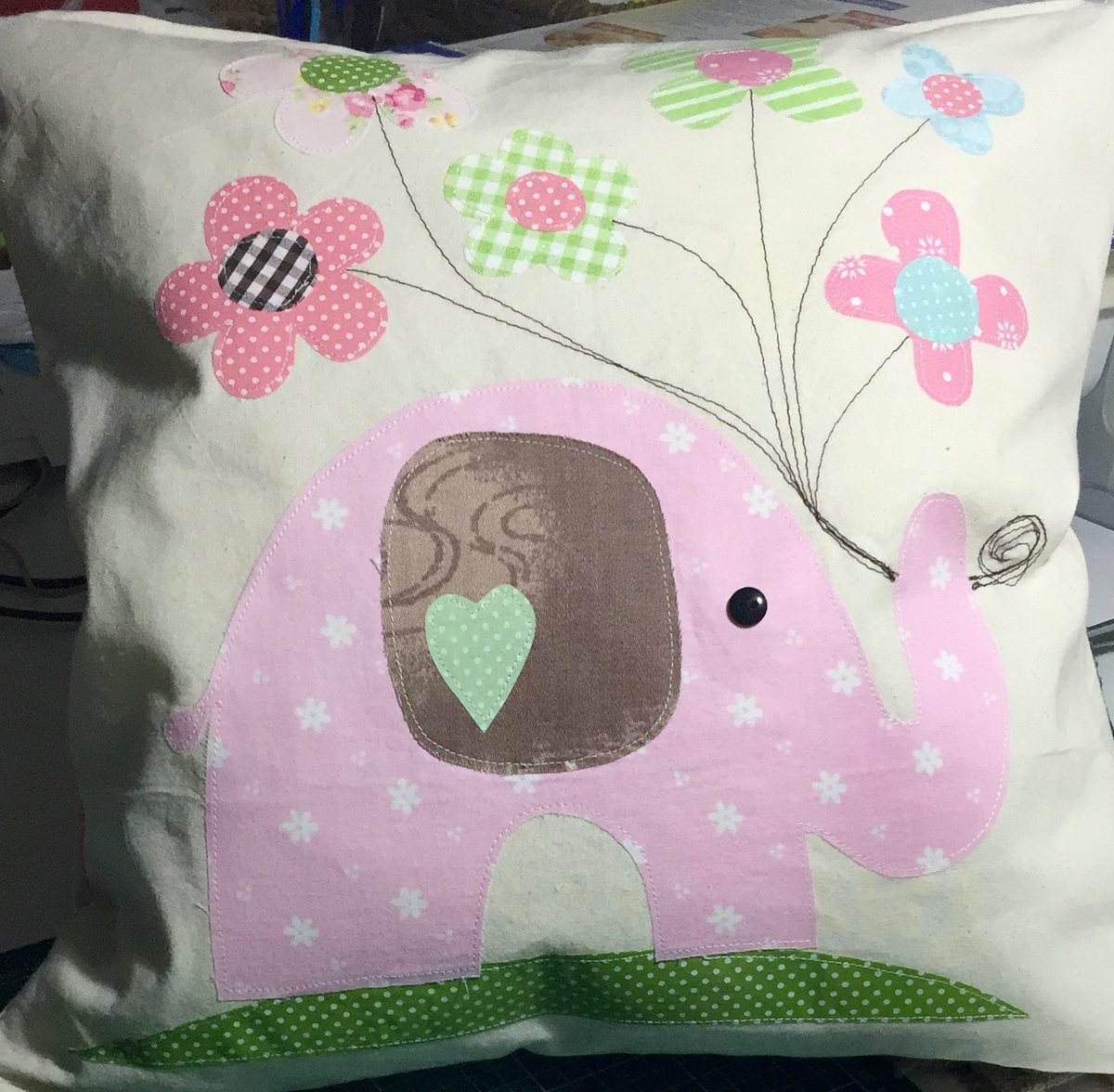 Cojín blanco con un elefante rosado y globos aplicados en tela