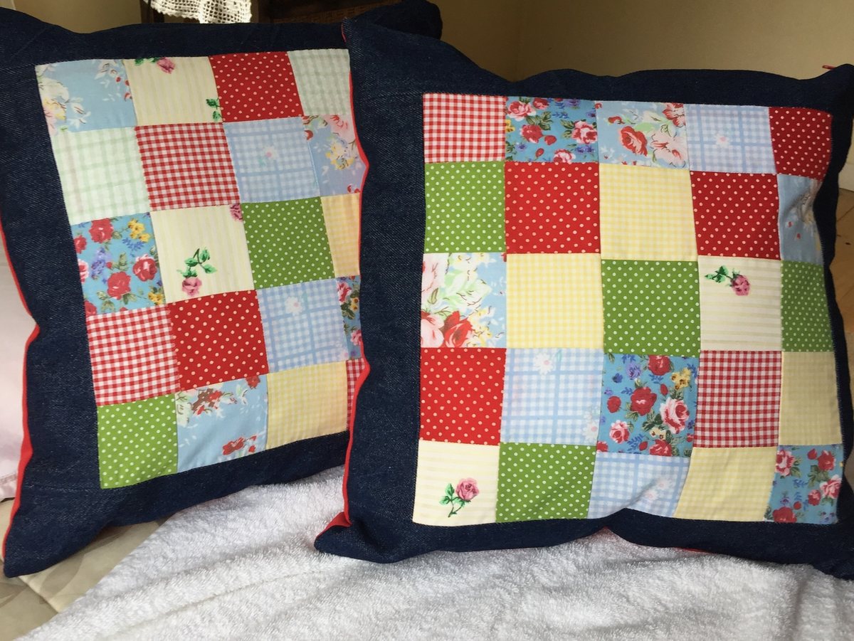 Dos cojines de patchwork con borde azul marino, en telas rojas y verdes