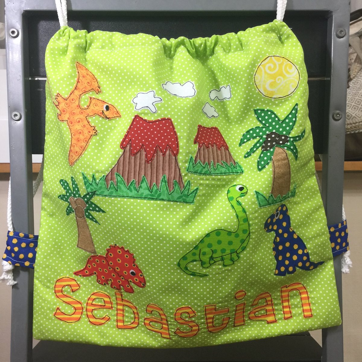 Morral verde con dinosaurios y el nombre Sebastián