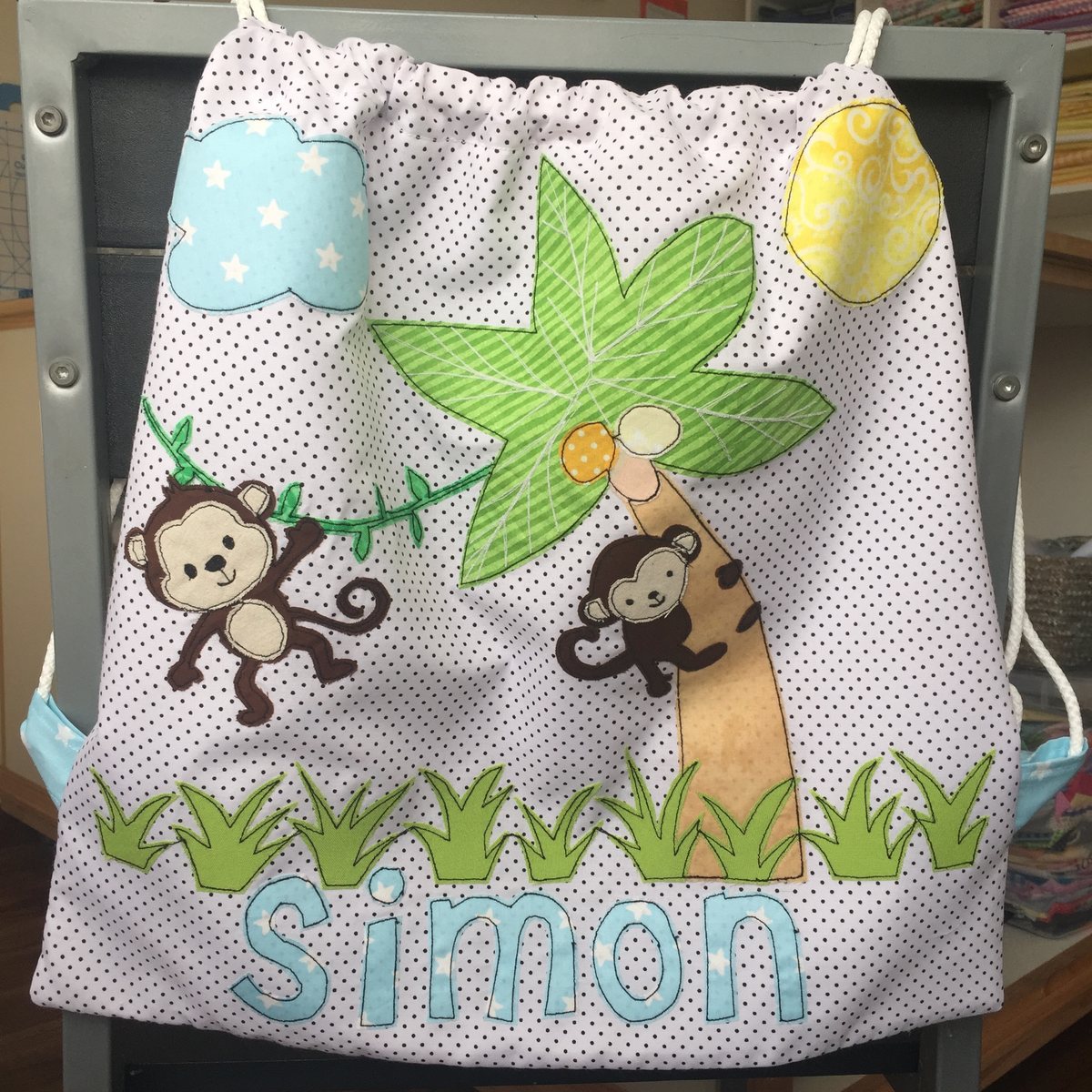 Morral gris con monitos y una jirafa y el nombre Simón
