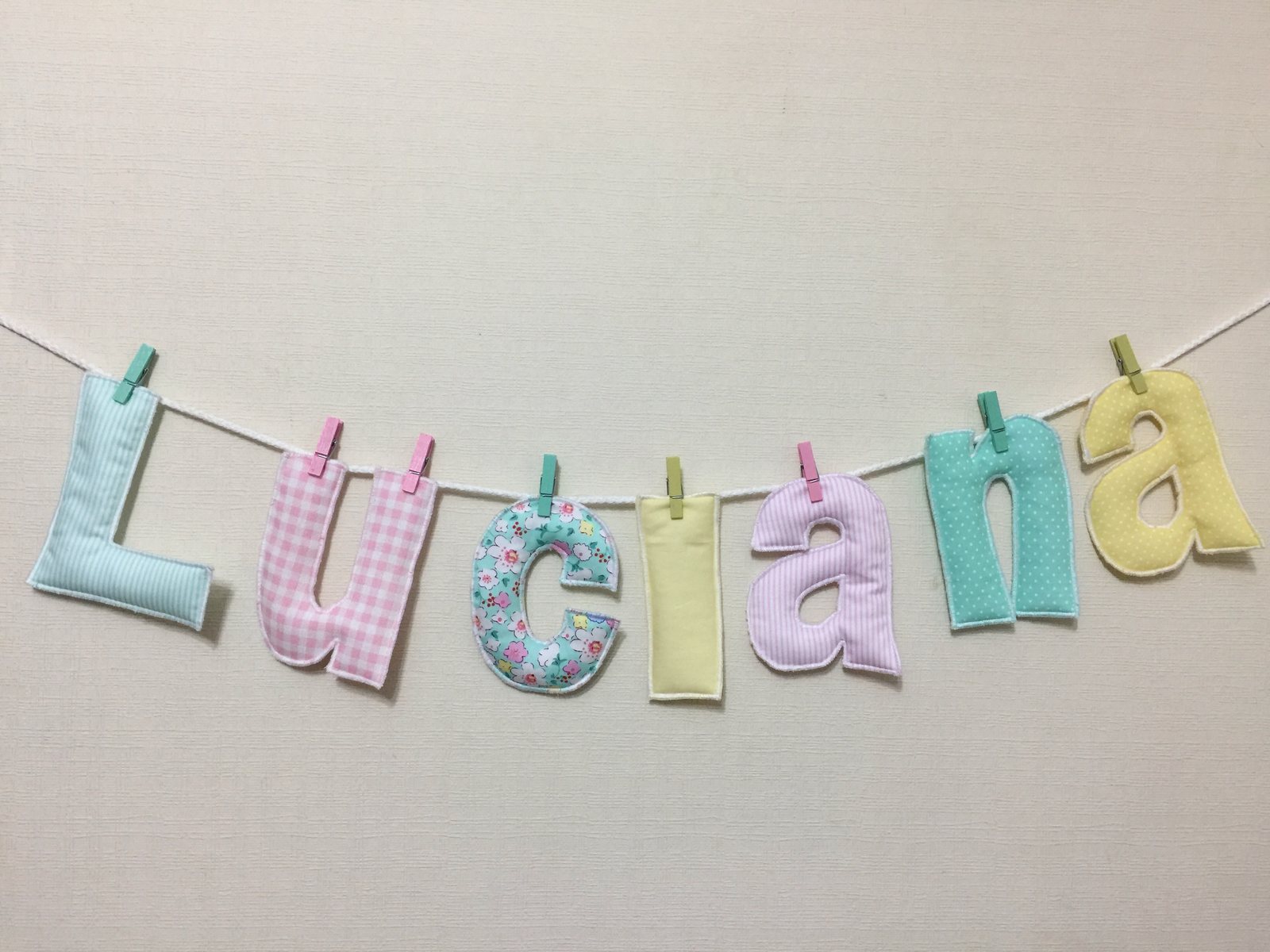 Guirnalda con el nombre Luciana en letras de tela pastel colgada de un cordel